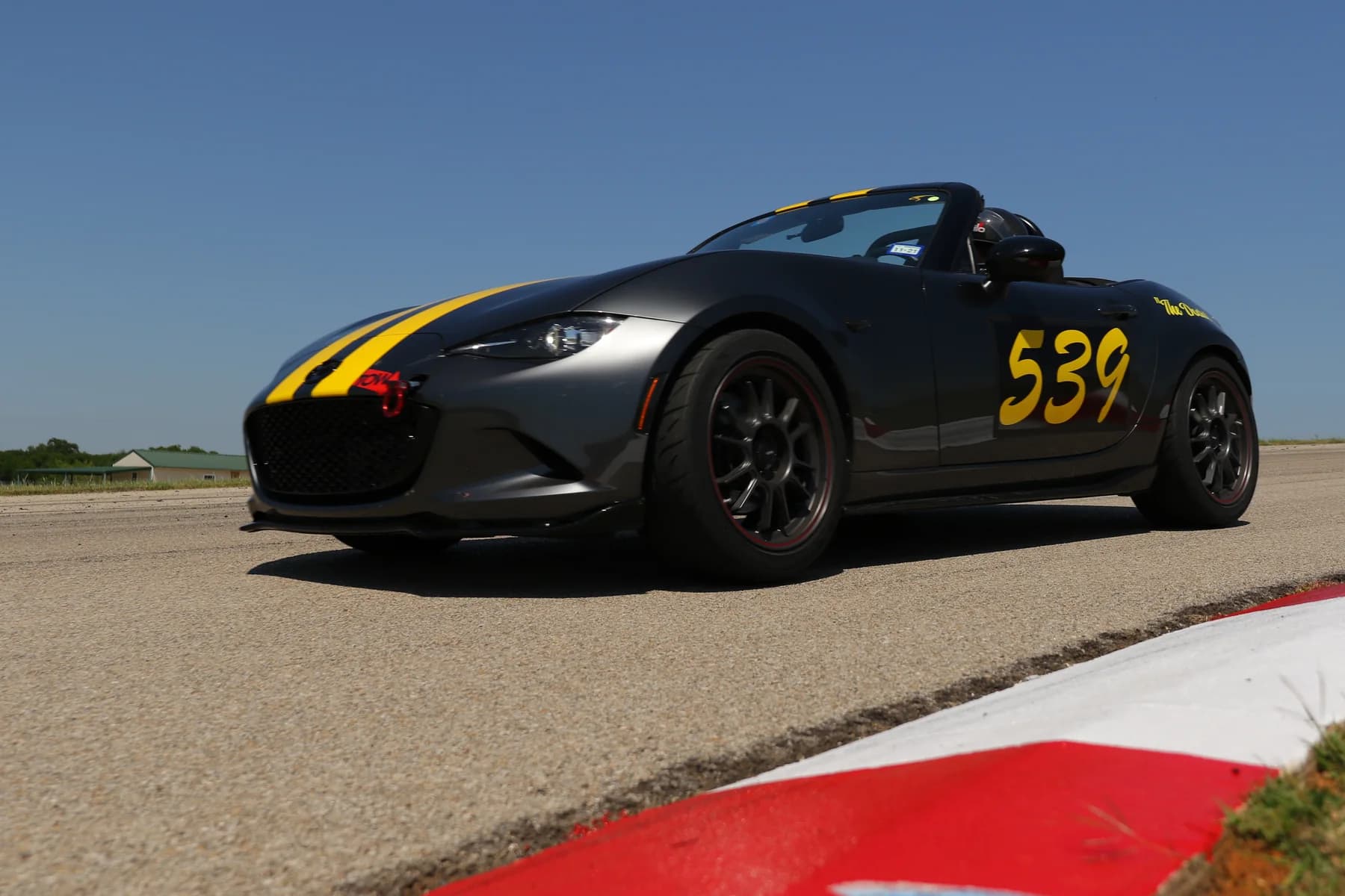 A black 539-branded sports car beside a red-and-white track curb